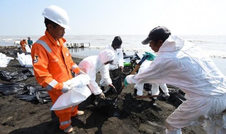 Pekerja Pertamina sedang membersihkan tumpahan minyak anjungan lepas pantai YY PHE ONWJ di wilayah Karawang, Jawa Barat.