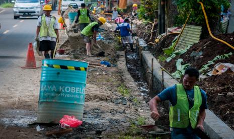 Pekerja menyelesaikan pembangunan drainase. 