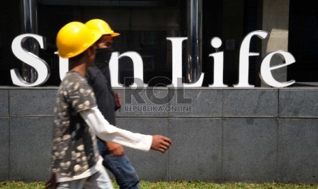 Pekerja sedang melintas didepan Menara Sunlife, Jakarta, Ahad (4/10). 