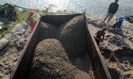 Pekerja sedang mengangkut pasir sebagai salah satu hasil pertambangan.