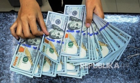  Pekerja sedang menghitung mata uang dolar di money change. ilustrasi 