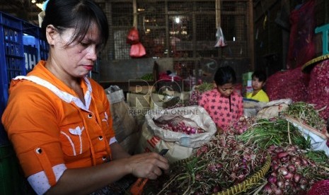 Pekerja sedang mengupas bawang merah di pasar Induk, Jakarta, Senin (14/12). 