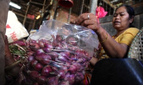 Pekerja sedang mengupas bawang merah di pasar Induk, Jakarta, Senin (14/12). 