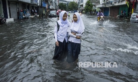 Pelajar berjalan melintasi air banjir di kawasan Sawah Besar, Jakarta, Selasa (21/2).