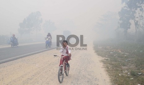 Pelajar berjalan menembus kabut asap di kawasan Rimbo Panjang, Tambang, Kampar, Riau, Selasa (1/9). Akibat Kabut asap kebakaran lahan gambut, sudah mulai menggangu lalu lintas jalan karena jarak pandang yang terbatas.