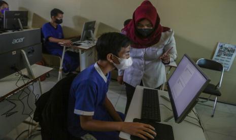 Pelajar didampingi pengajar mengerjakan soal Ujian Sekolah Berbasis Komputer (USBK) di SLB Negeri 1 Palangka Raya, Kalimantan Tengah, Rabu (11/5/2022). Dinas Pendidikan Provinsi Kalimantan Tengah menggelar USBK secara tatap muka untuk menilai standar kompetensi kelulusan peserta didik pada jenjang SMK dan SLB yang diikuti sebanyak 11.721 siswa dengan tetap menerapkan protokol kesehatan COVID-19