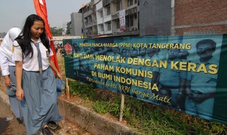 Pelajar melintas di dekat spanduk penolakan paham komunis di daerah Ciledug, Tangerang, Banten, Kamis (1/10). 