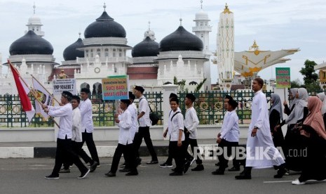 Pelajar melintas di depan Masjid Raya Baiturrahman saat mengikuti pawai keliling kota di Banda Aceh, Aceh, Selasa (30/4/2019). 