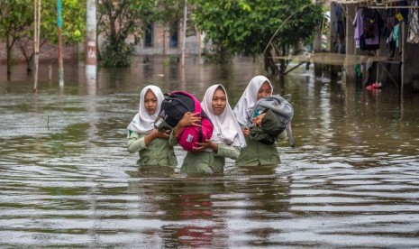 Pelajar menembus jalan desa yang terendam banjir di Dusun Sayung Kulon, Sayung, Demak, Jawa Tengah, Kamis (15/2). 