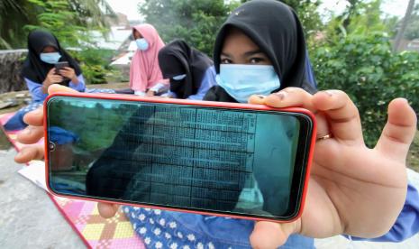 Pelajar menunjukkan bahan pembelajaran dalam jaringan (daring) di atas atap rumah warga di Desa Meuria Paloh, Aceh, Sabtu (31/7/2021). Para pelajar di daerah pedalaman tersebut kesulitan mengikuti proses belajar mengajar secara daring di masa pandemi Covid-19 akibat keterbatasan kuota dan jaringan internet dan terpaksa mencari sinya di ketinggian dan tempat terbuka. (Ilustrasi)