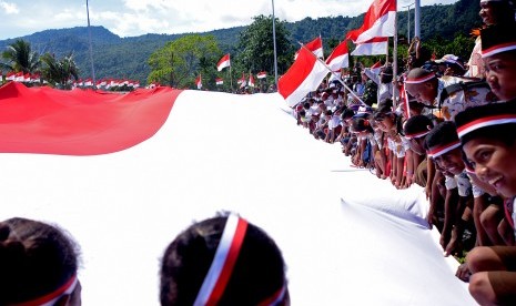 Pelajar perbatasan RI-PNG membentangkan bendera merah putih di perbatasan Skouw-Wutung, Republik Indonesia - Papua New Guinea (PNG), Rabu (30/11).