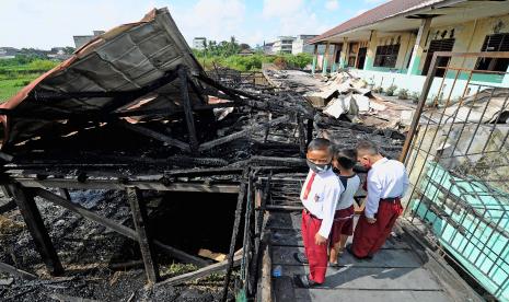 Pelajar SDN 164 Kota Jambi melihat sisa bekas kebakaran bangunan sekolahnya di Jambi Timur, Jambi, Senin (9/5/2022). Kegiatan belajar untuk 85 pelajar di SDN 164 Kota Jambi dipindahkan ke SDN 190 Kota Jambi atau SD terdekat, pascakebakaran sekolah pada Sabtu (7/5/2022) malam.