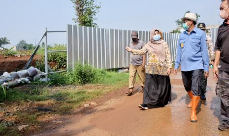 Pelaksana tugas (Plt.) Kepala Dinas Pekerjaan Umum dan Penataan Ruang (PUPR) Kota Depok, Citra Indah Yulianty (kiri) menunjukkan lahan tanah urugan penyebab licinnya jalan raya. 