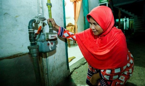 Pelanggan gas bumi rumah tangga PT Perusahaan Gas Negara Tbk (PGN) sedang mengecek pemakaian gas pada meteran gas bumi yang terpasang di rumahnya. 