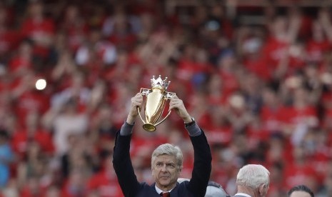 Pelatih Arsenal Arsene Wenger mengangkat piala yang dipersembahkan untuknya usai laga Arsenal menghadapi Burnley di Emirates Stadium, London, Ahad (6/5). Pertandingan tersebut menjadi laga terakhir menukangi Arsenal di Emirates Stadium