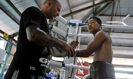 Pelatih Craig Christian (kiri) memasangkan sarung tinju pada petinju Daud Yordan saat latihan di Kuta, Bali, Rabu (6/1).