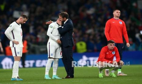 Pelatih kepala Gareth Southgate (tengah) dari Inggris menghibur Jadon Sancho setelah gagal mencetak gol saat adu penalti pada final UEFA EURO 2020 antara Italia dan Inggris di London, Inggris, Senin (12/7) dini hari WIB.