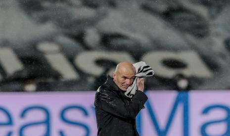  Pelatih kepala Real Madrid Zinedine Zidane menyeka air hujan di wajahnya dengan handuk saat pertandingan sepak bola La Liga Spanyol antara Real Madrid melawan Betis di stadion Alfredo di Stefano di Madrid, Spanyol, Sabtu, 24 April 2021.