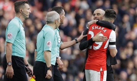 Pelatih Manchester City, Pep Guardiola memeluk gelandang Arsenal, Granit Xhaka seusai laga Liga Primer di stadion Emirates, Ahad (2/4). Laga berakhir imbang 2-2.