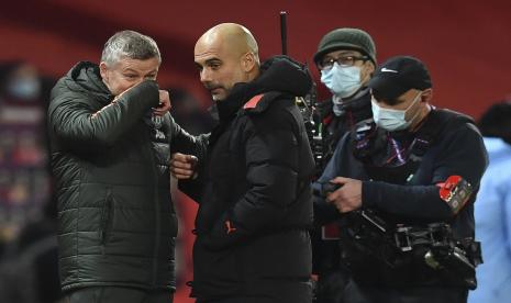 Pelatih Manchester United (MU) Ole Gunnar Solskjaer (kiri) berbincang dengan juru taktik Manchester City Josep Guardiola setelah kedua tim bentrok pada lanjutan Liga Primer Inggris 2020/2021 di Old Trafford, Ahad (13/12).