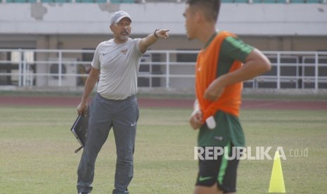 Pelatih timnas U-19 Indonesia Fakhri Husaini (kiri) memberikan instruksi kepada para pemainnya saat latihan di Stadion Pakansari, Cibinong, Bogor, Jawa Barat, Senin (30/9/2019). 