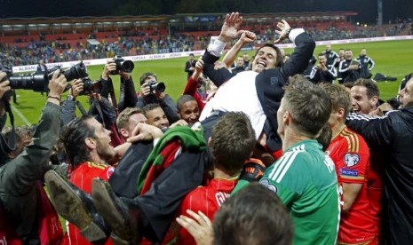 Pelatih Timnas Wales, Chris Coleman, melakukan selebrasi bersama pemainnya usai lolos ke putaran final Piala Eropa 2016 setelah mengalahkan Bosnia di Zenica pada Sabtu (10/10). 