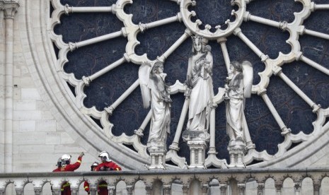 Pemadam kebakaran di dekat jendela Katedral Notre Dame, Selasa (16/4), di Paris. Kebakaran menghabiskan sebagian besar gereja yang telah berdiri 900 tahun.