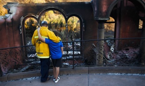 Pemadam kebakaran Terry Sanders dan putranya Isaac kehilangan rumahnya akibat kebakaran. Mereka melihat rumah tetangga yang juga terbakar di Santa Rosa, California, (14/10).