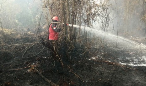 Pemadaman titik api di hutan Rimbo Panjang, Kabupaten Kampar, Riau. Selasa (17/9).