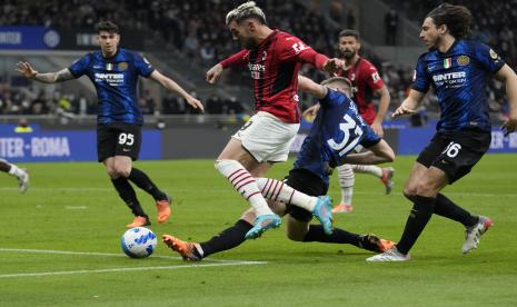 Pemain AC Milan Theo Hernandez, kiri, dan pemain Inter Milan Milan Skriniar berebut bola dalam pertandingan sepak bola leg kedua semifinal Piala Italia antara Inter Milan dan AC Milan, di stadion San Siro, di Milan, Italia, Selasa, 19 April, 2022.