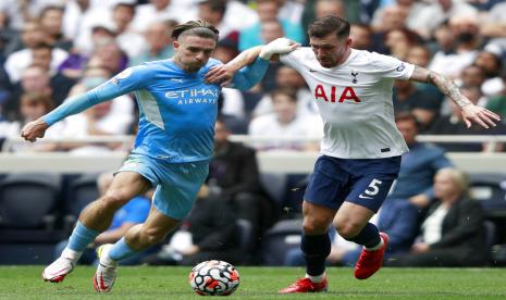 Pemain anyar Manchester City Jack Grealish (kiri) berduel bola dengan gelandang Tottenham Hotspur Pierre Emile Hobjberg dalam pertandingan Liga Primer Inggris 2021/2022 di Stadion Tottenham Hotspur, Ahad (15/8).