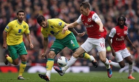 Pemain Arsenal, Aaron Ramsey (kanan), terlihat berebut bola dengan seorang pemain Norwich City. Pada laga Liga Primer yang berakhir Ahad (21/10) dini hari itu Arsenal takluk 1-0.