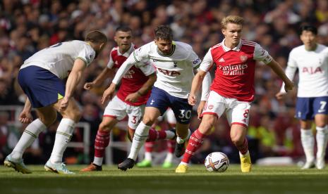 Pemain Arsenal Martin Odegaard, kanan, berlari dengan bola melewati pemain Tottenham Rodrigo Bentancur, tengah, dan pemain Tottenham Eric Dier selama pertandingan sepak bola Liga Inggris antara Arsenal dan Tottenham Hotspur, di Emirates Stadium, di London, Inggris, Sabtu, 1 Oktober 2022 