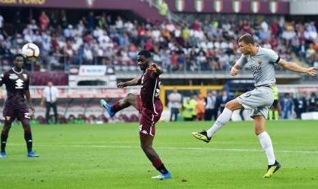 Pemain AS Roma Edin Dzeko (kanan) melesakkan tendangan yang menghasilkan gol ke gawang Torino dalam pertandingan yang digelar di Turin Olympic Stadium, Italia, Ahad (19/8). Roma menang 1-0 di pertandingan ini 