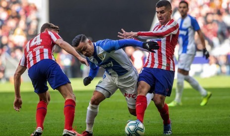 Pemain Atletico Madrid Angel Correa (kanan) dan Marcos Llorente (kiri) berebut bola dengan pemain Leganes Roque Mesa dalam pertandingan di Liga Spanyol, Ahad (26/1).