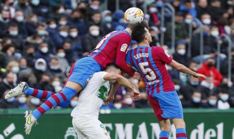 Pemain Barcelona, Gerard Pique (kiri) dan Sergio Busquets (kanan), menghadang pemain Elche di laga La Liga Spanyol di Stadion Martinez Valero pada Ahad (6/3).