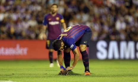  Pemain Barcelona Luis Suarez (depan) memperbaiki rumput yang rusak kala tandang ke Markas Real Valladolid di Nuevo Jose Zorilla Stadium. Buruknya kondisi lapangan membuat pihak Liga Spanyol melakukan investigasi standardisasi untuk kompetisi La Liga 