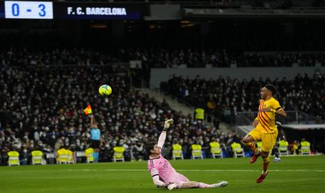 Striker Barcelona Pierre-Emerick Aubameyang (kanan) mencetak gol keempat timnya di depan kiper Real Madrid Thibaut Courtois selama pertandingan sepak bola La Liga Spanyol antara Rial Madrid dan FC Barcelona di Stadion Santiago Bernabeu di Madrid, Spanyol, Ahad, 20 Maret 2022 atau Senin (21/3/2022) dini hari WIB.