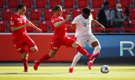 Pemain Bayern Munich Alphonso Davies (kanan) berusaha merebut bola dengan para pemain FC Union Berlin dalam pertandingan sepak bola Bundesliga Jerman antara Union Berlin dan Bayern Munich di Berlin, Jerman, Ahad (17/5). Dalam pertandingan tersebut Bayern Munich menang 2-0. Bundesliga Jerman menjadi liga sepak bola utama pertama di dunia yang melanjutkan setelah suspensi dua bulan karena pandemi Covid-19.  