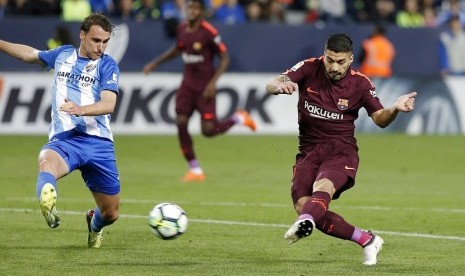 Pemain bertahan Malaga, Ignasi Miquel (kiri) mencoba menahan tendangan Luis Suarez dalam pertandingan La Liga, Sabtu (10/3) waktu setempat 