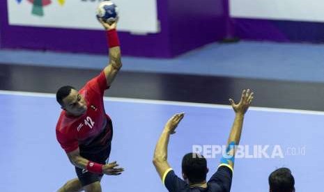 Pemain bola tangan putra Indonesia Viktorius Rafael Tolang (atas) berusaha melempar bola melewati hadangan pemain bola tangan Malaysia saat pertandingan babak utama grup 3 Bola Tangan Asian Games ke-18 tahun 2018 di GOR Popki, Cibubur, Jakarta, Minggu (26/8). 