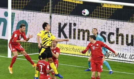 Pemain Borussia Dortmund Mats Hummels (tengah) menanduk bola saat bertanding melawan Bayern Muenchen.