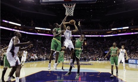 Pemain Charlotte Bobcats, Gerald Henderson (tengah), melepaskan tembakan di bawah penjagaan pemain Boston Celtics, Brandon Bass (kiri) dan Jeff Green (kanan), di laga NBA di Charlotte pada Selasa (12/3). 