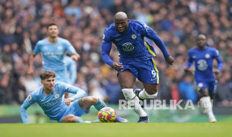 Striker Chelsea Romelu Lukaku (tengah) mengambil bola melewati pemain Manchester City John Stones (kiri) saat pertandingan sepak bola Liga Inggris antara Manchester City dan Chelsea di Stadion Etihad di Manchester, Inggris, Sabtu (15/1/2022). Chelsea kalah 0-1 di laga itu.