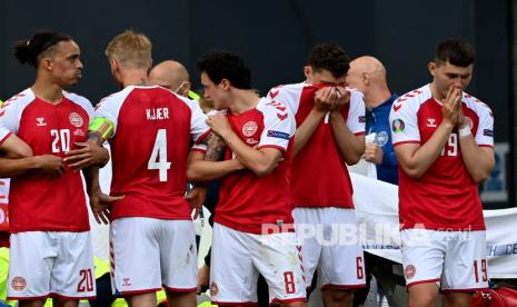 Pemain Denmark membuat dinding di sekitar rekan setimnya Christian Eriksen yang dibantu oleh petugas medis pada pertandingan grup B kejuaraan sepak bola Euro 2020 antara Denmark dan Finlandia di Stadion Parken di Kopenhagen, Sabtu (12/6).