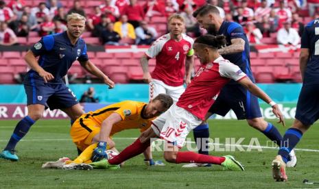 Pemain Denmark Yussuf Poulsen (kanan tengah) berebut bola dengan kiper Finlandia Lukas Hradecky pada pertandingan grup B kejuaraan sepak bola Euro 2020 antara Denmark dan Finlandia di stadion Parken di Kopenhagen, Sabtu (12/6).