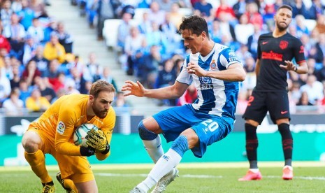 Pemain Espanyol Bernardo Espinosa (tengah) berusaha mengganggu kiper Atletico Madrid Jan Oblak dalam pertandingan Liga Spanyol di Barcelona, Ahad (1/3). 