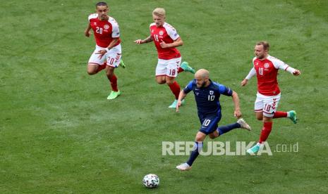 Pemain FinlandiaTeemu Pukki (bawah) mengontrol bola saat pemain Denmark Yussuf Poulsen (kiri) Daniel Wass (tengah) dan Christian Eriksen berlari untuk menghentikannya pada pertandingan grup B kejuaraan sepak bola Euro 2020 antara Denmark dan Finlandia di stadion Parken di Kopenhagen, Denmark, Sabtu (12/6).