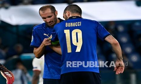 Pemain Italia Giorgio Chiellini (kiri) memberikan ban kapten kepada rekan setimnya Leonardo Bonucci sebelum meninggalkan lapangan saat pertandingan grup A kejuaraan sepak bola Euro 2020 antara Italia dan Swiss di stadion Olimpiade di Roma, Kamis (17/6) dini hari WIB.