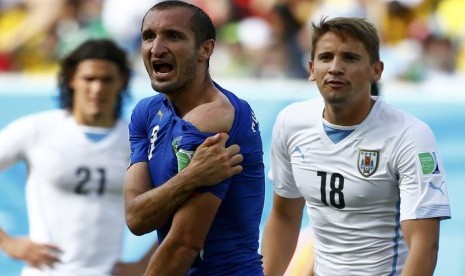 Pemain Italia, Giorgio Chiellini, memperlihatkan bahunya yang diklaim digigit striker Uruguay, Luis Suarez, selama pertandingan terakhir Grup D Piala Dunia 2014 Brasil di Arena Dunas, Natal, Selasa (24/6). 